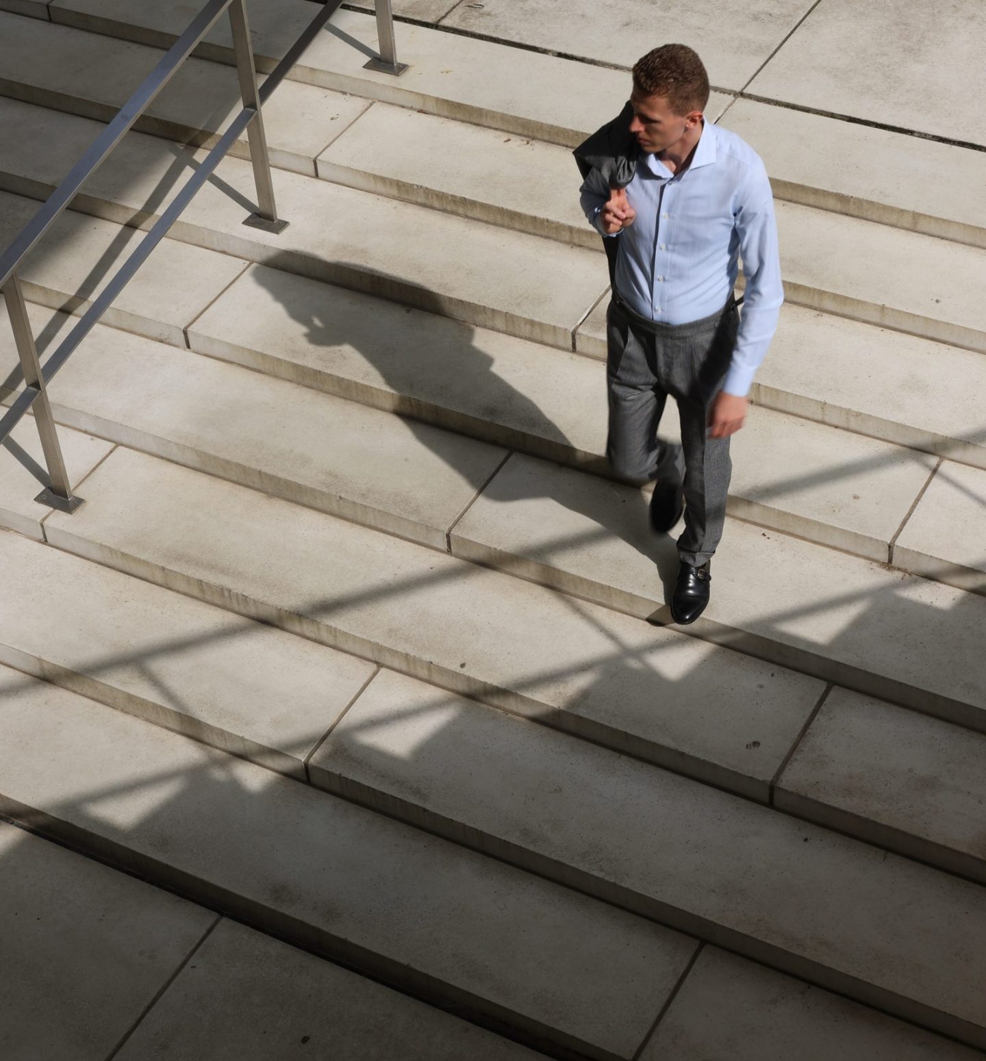 Man in grey suit walking down some stairs